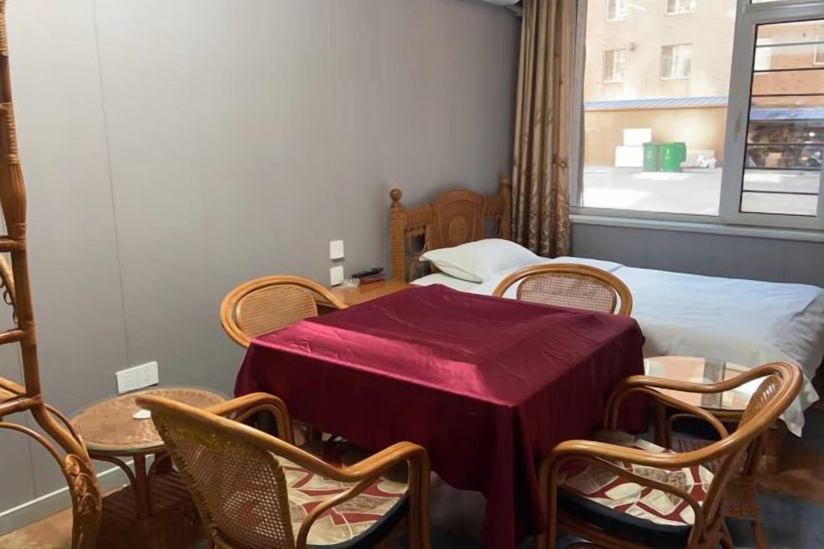 Quarto com uma cama, uma mesa com toalha e quatro cadeiras de vime.