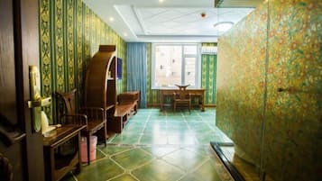 Una habitación con papel tapiz estampado, un aparador de madera, una mesa y sillas.