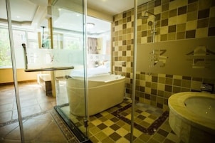 Un baño moderno con ducha de vidrio, una bañera independiente y una zona separada para el lavamanos.