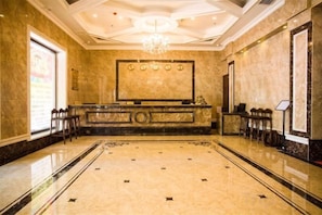 A lobby with a reception desk, seating area, and a chandelier.