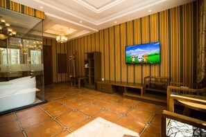 Un baño moderno con un espejo grande, una bañera y un televisor montado en la pared.