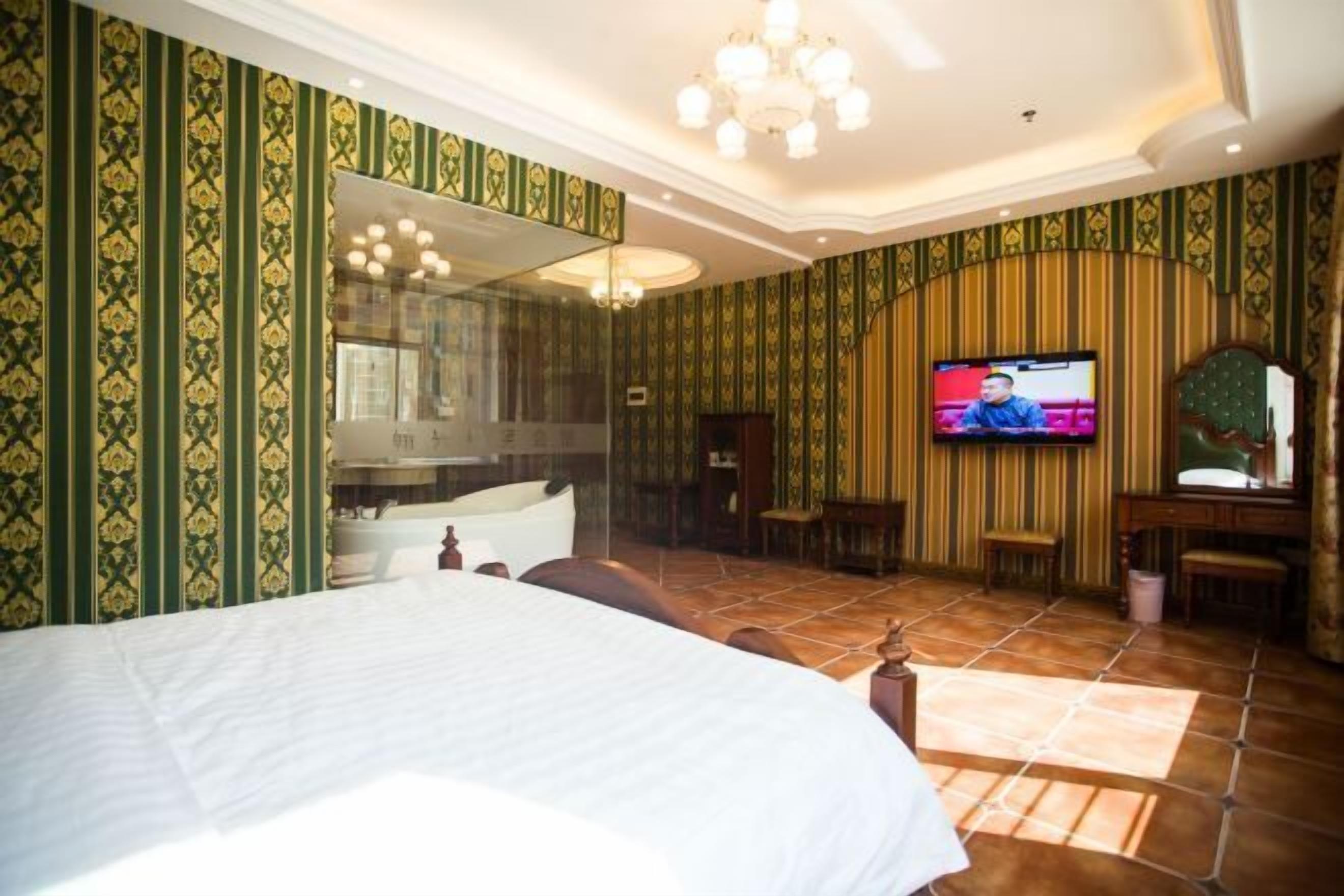 A hotel room with a large bed, a television, a mirror, and a vanity with a sink.