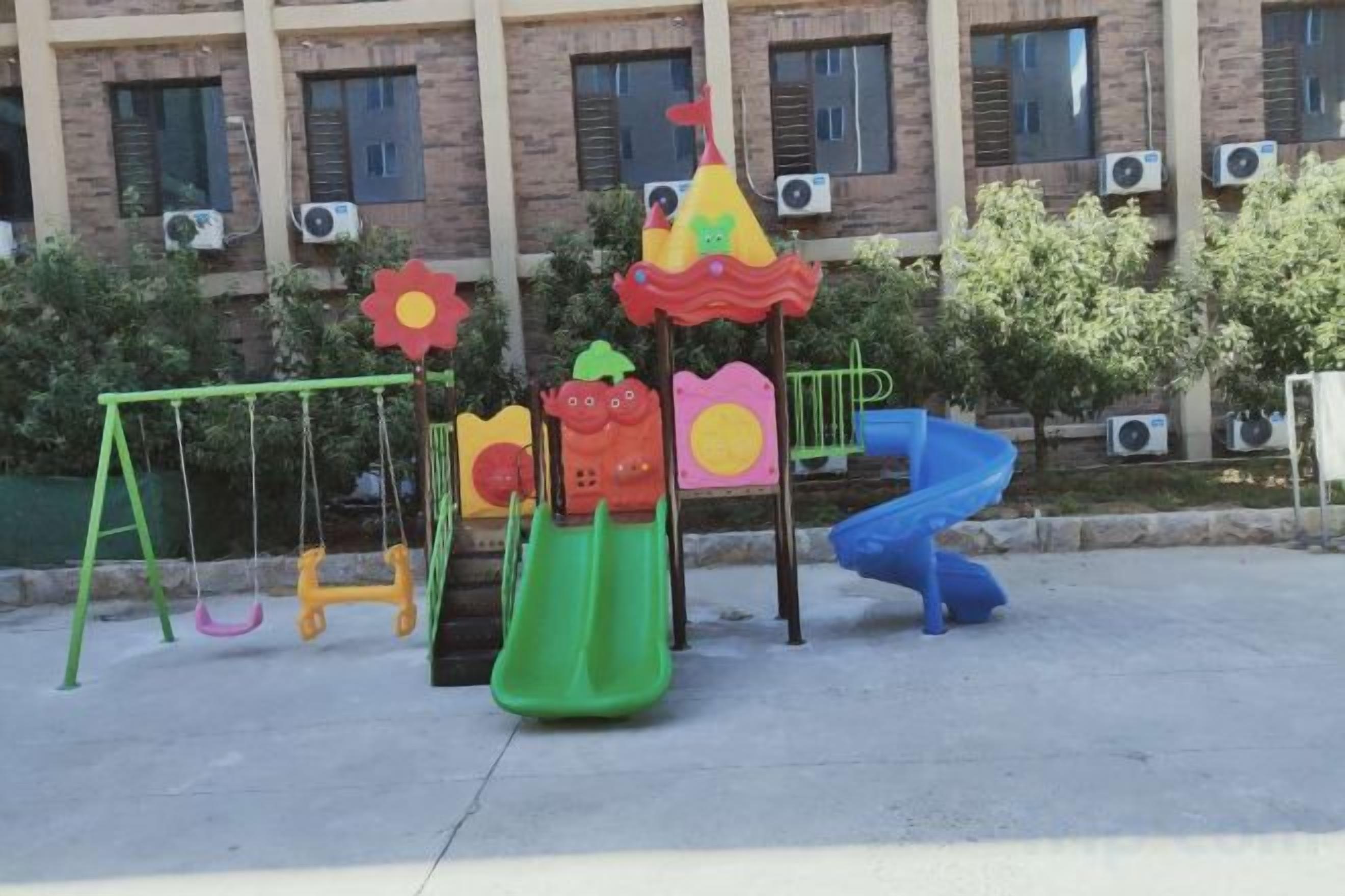 Une aire de jeux avec des balançoires, des toboggans et des structures d’escalade.
