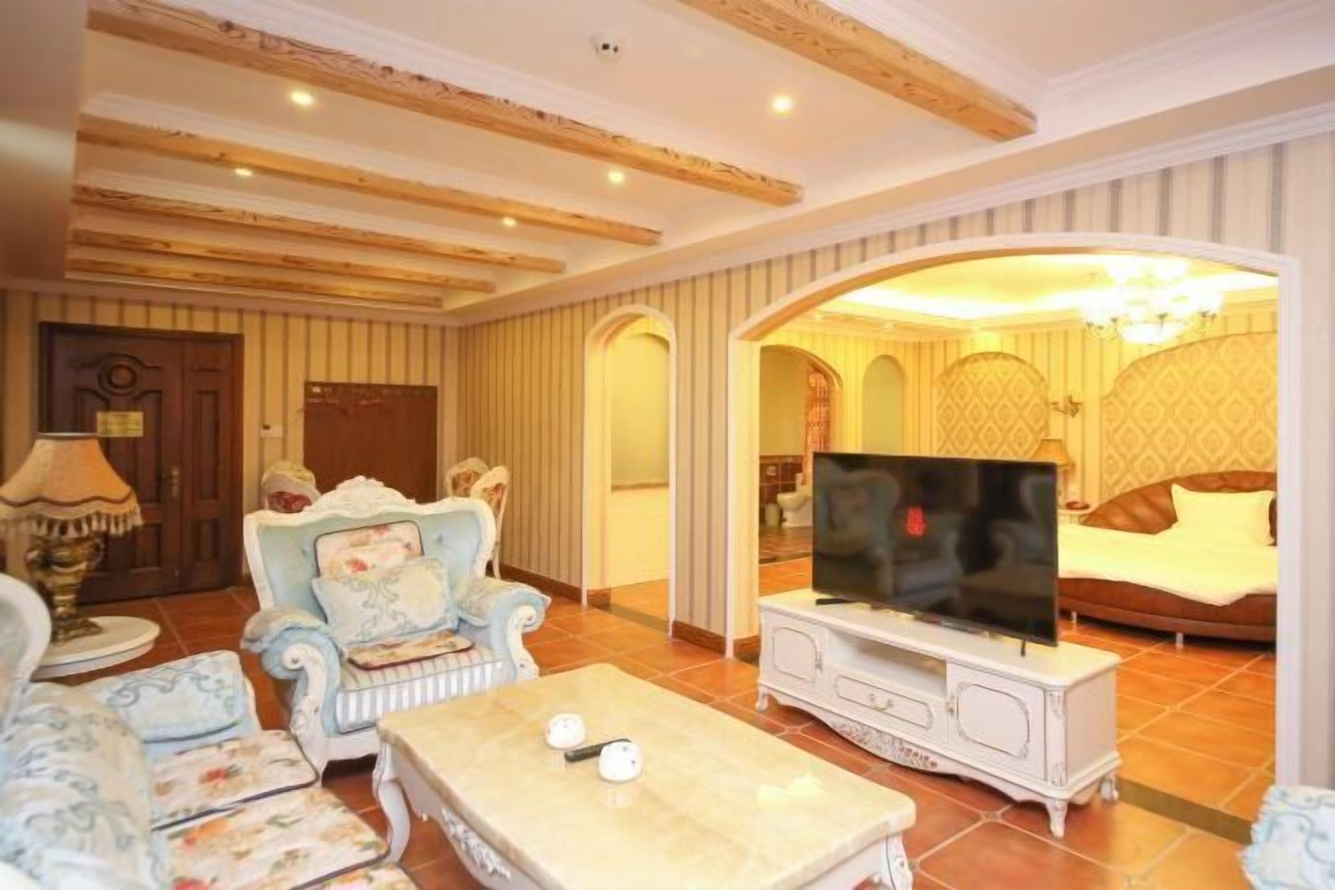 A living room with a television, a sofa, a coffee table, and a patterned armchair.