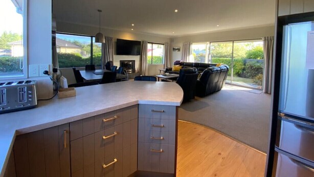 A modern kitchen with a central island, built-in appliances, and a dining area with a view.
