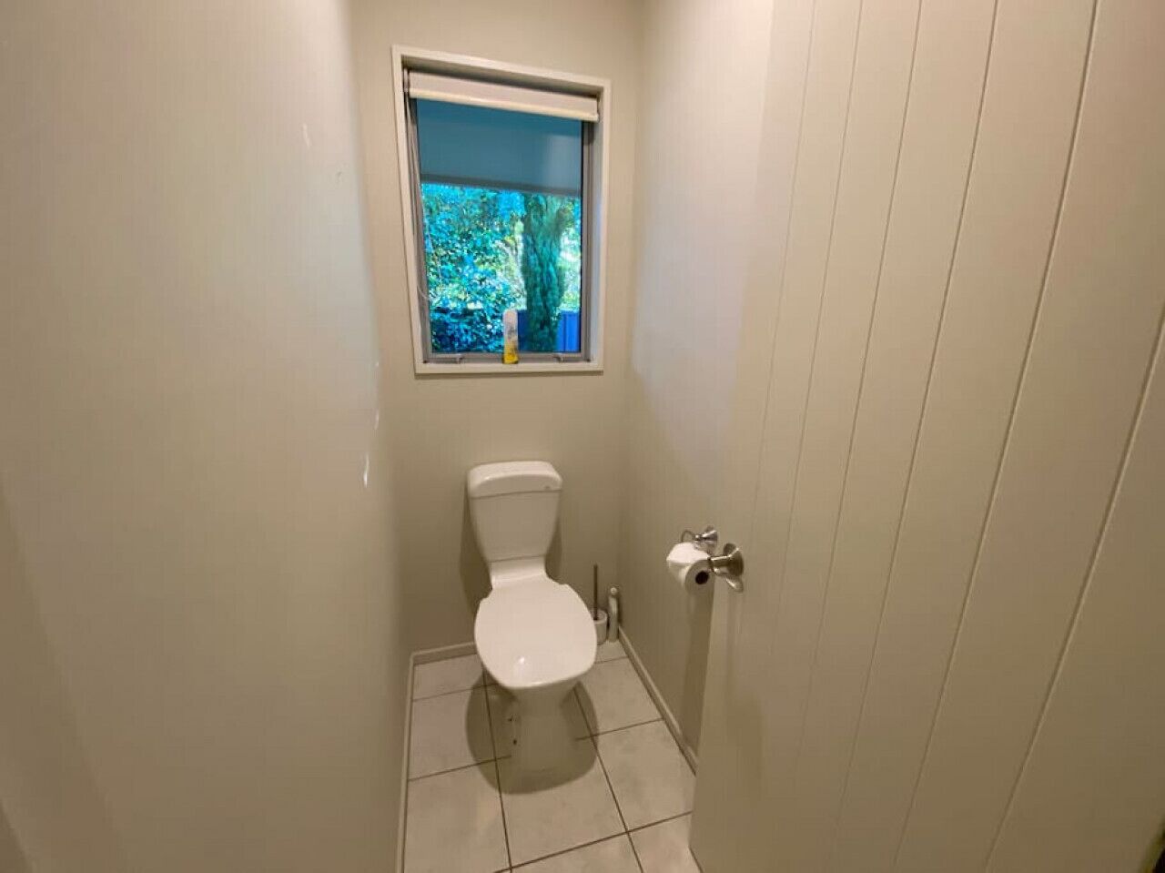 A small, clean bathroom with a toilet, a window, and a door.