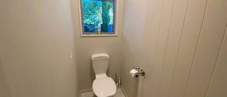 A small, clean bathroom with a toilet, a window, and a door.