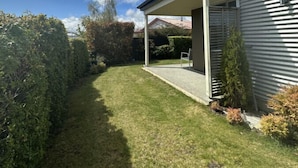 A modern house with a covered patio, a well-maintained lawn, and a clear sky.