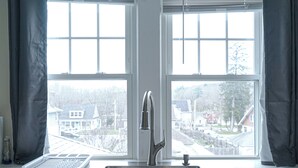 A kitchen with a stainless steel sink, a kettle, and a window with curtains. - 79-4 spacious studio Walk to backus hospital and downtown (Norwich)
