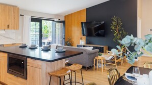 Una cocina moderna con una isla central, armarios de madera y un comedor con sofá y sillas.