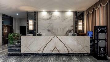 A marble reception desk with a waterfall mural, a reception area with a plant, and a black information kiosk.