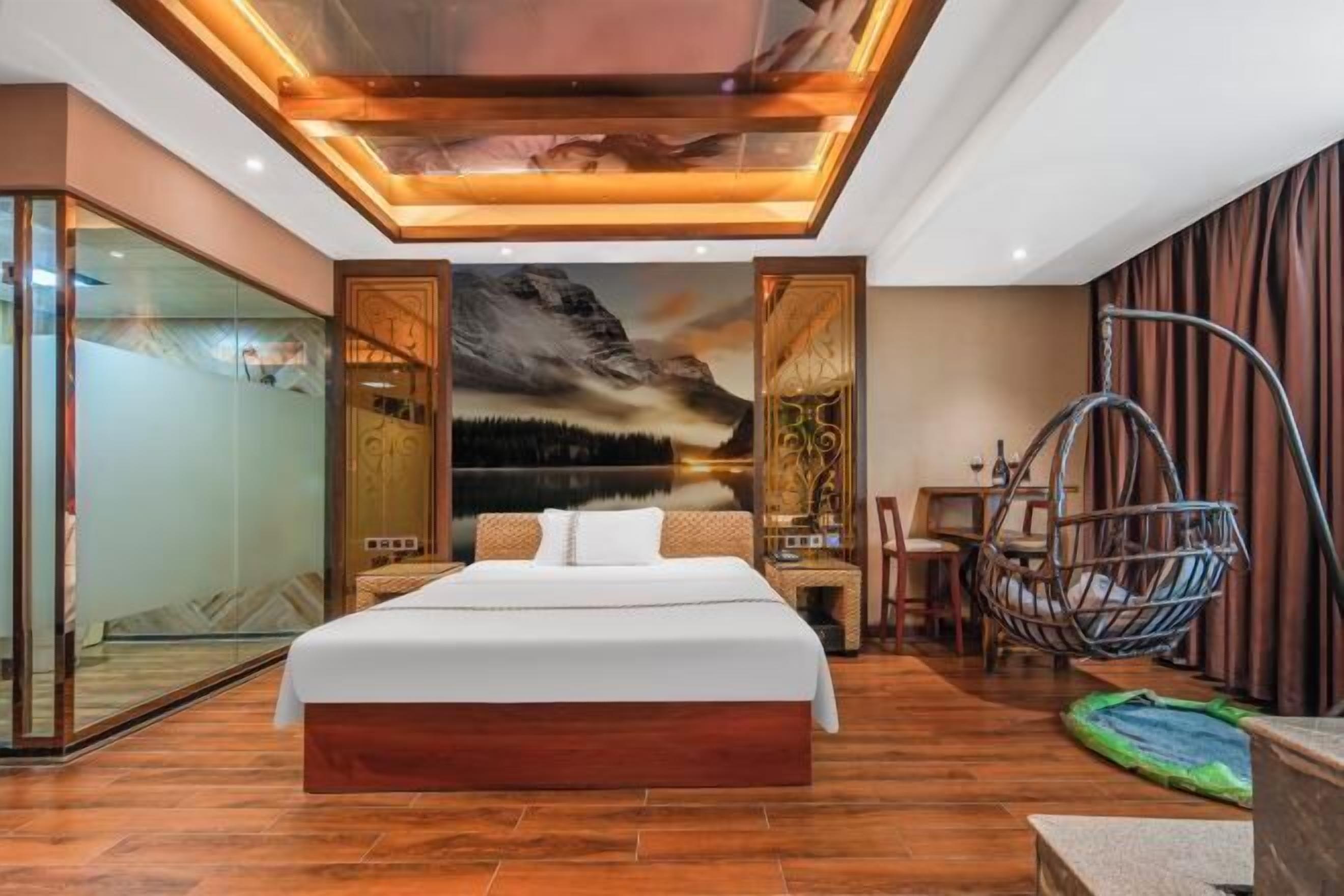 A modern bedroom with a large bed, a hanging chair, and a glass wall.
