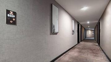 A long, narrow hotel corridor with a textured wall, a sign with the number 8509, and framed pictures on the walls.