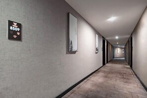 A long, narrow hotel corridor with a textured wall, a sign with the number 8509, and framed pictures on the walls. - Junhao Hotel (Linwu)