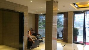 Un vestíbulo con mostrador de recepción, zona de estar y grandes ventanales con vistas al exterior.