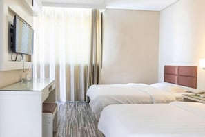 A hotel room with two beds, a desk with a flat-screen TV, a bedside table with a lamp, and a window with curtains. - Fuguilou Hotel (Gucheng)