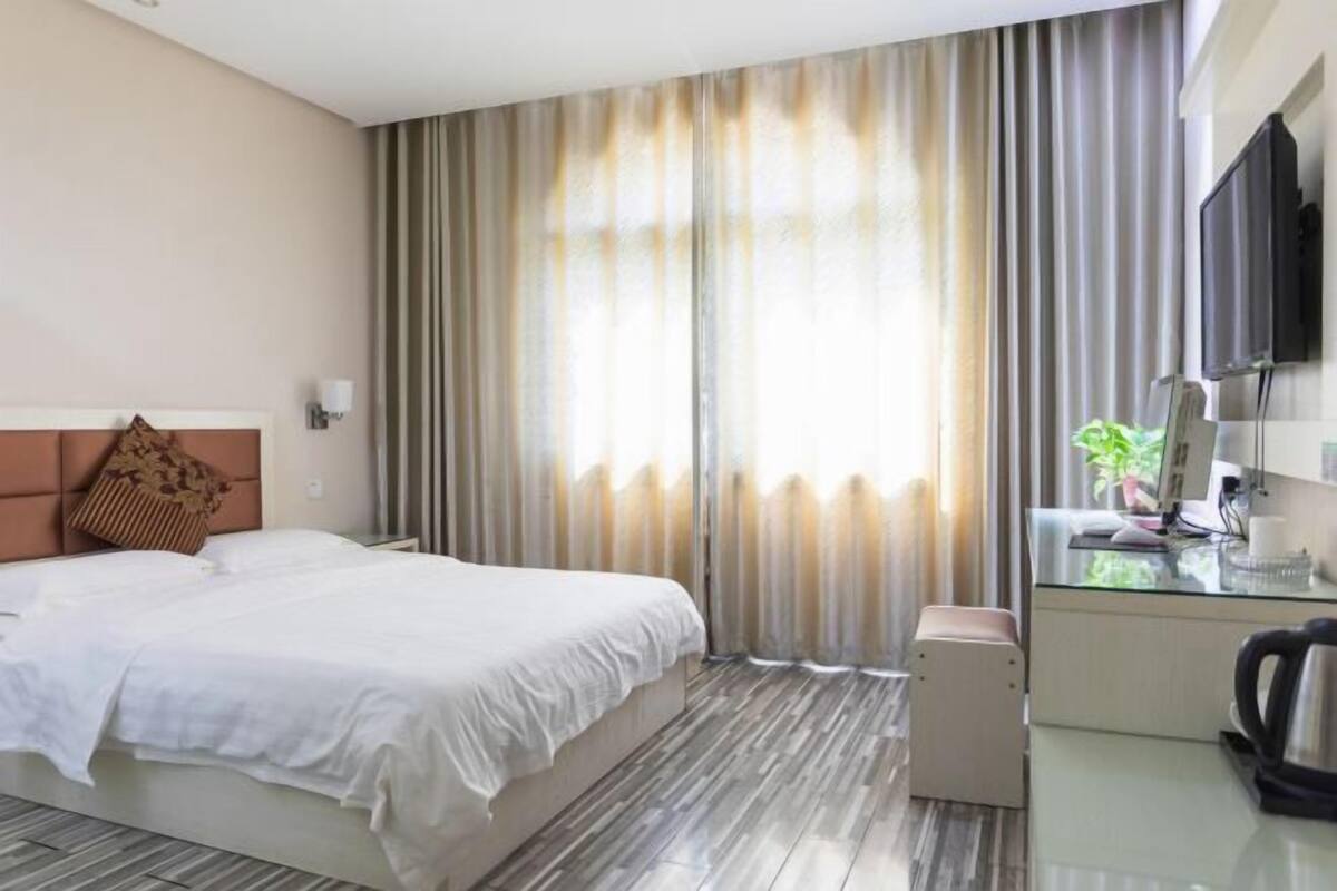 A hotel room with a bed, a desk with a computer, a coffee maker, and a TV.