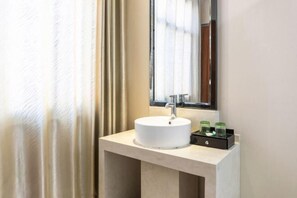 A bathroom with a white sink, a mirror, and a small black tray with green bottles. - Fuguilou Hotel (Gucheng)
