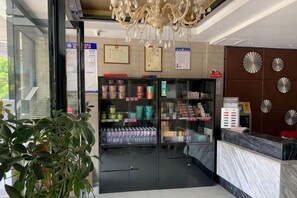 A hotel reception area with a glass door entrance, a reception desk, a chandelier, and a vending machine. - Fuguilou Hotel (Gucheng)