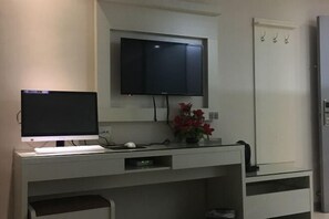 A modern room with a flat-screen TV mounted on the wall, a desk with a computer, and a small plant. - Fuguilou Hotel (Gucheng)