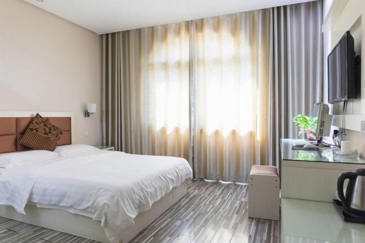 A hotel room with a bed, a desk with a computer, a coffee maker, and a TV.