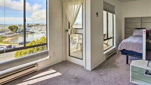A bedroom with a large window offering a view of a marina and boats.