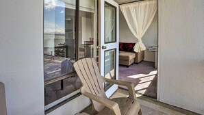 A balcony with a chair, a sliding glass door, and a view of the sea.