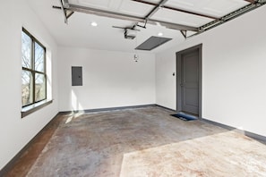 A spacious, well-lit room with a large window, a door, and a visible electrical panel.