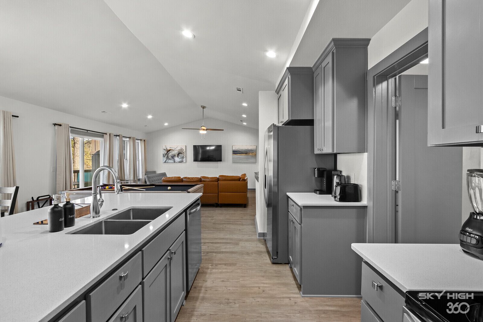 Una cocina moderna con una isla central, muebles grises y un horno empotrado.