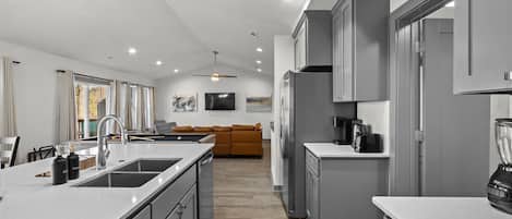 Una cocina moderna con una isla central, muebles grises y un horno empotrado.