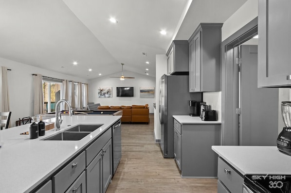 A modern kitchen with a central island, grey cabinetry, and a built-in oven.