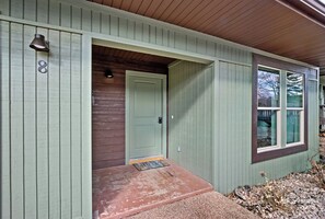 A single-story house with a green exterior, a front door, and a small porch area.