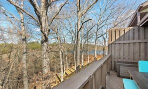 A wooden deck with a view of a lake and trees.