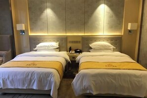 A hotel room with two beds, a wooden headboard, and a wall-mounted light fixture. - Dansha Hotel (Wuchuan)