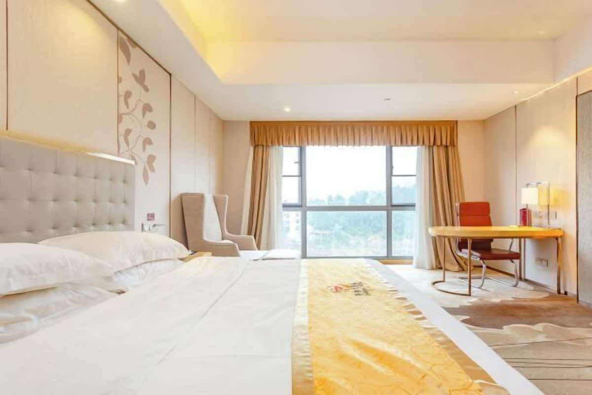 A hotel room with a large bed, a desk, and a chair.