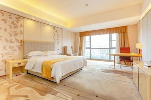 Una habitación de hotel moderna con una cama grande, un escritorio y vistas de la ciudad a través de amplios ventanales.