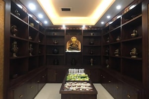 A room with shelves containing various items, a central display table, and a statue.