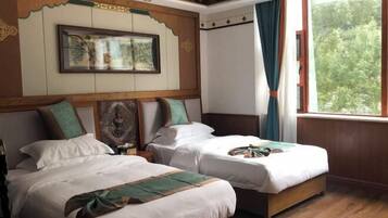 Una habitación con dos camas, un cuadro en la pared y una ventana con cortinas.