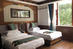 Una habitación con dos camas, un cuadro en la pared y una ventana con cortinas.