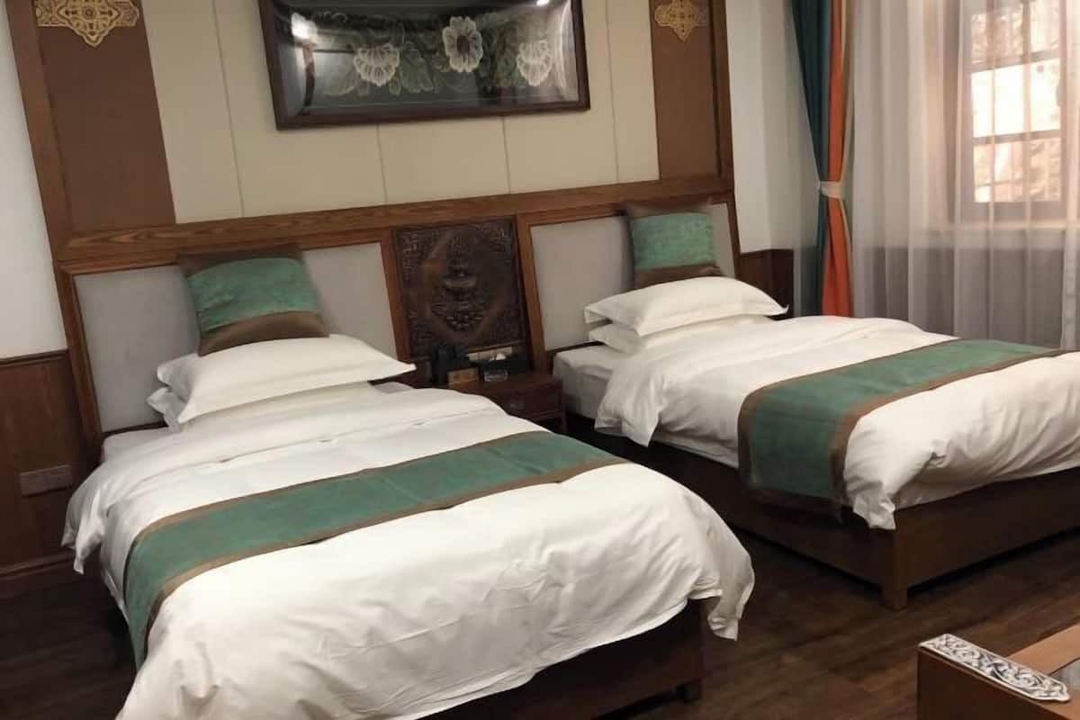 Ein Hotelzimmer mit zwei Betten, Holz-Kopfteilen und einer dekorativen Wandverkleidung.