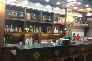 Un espace bar doté d’étagères remplies de bouteilles, de verres et de divers ustensiles de bar.