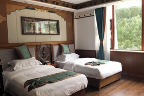 Een hotelkamer met twee bedden, een groot raam met gordijnen, een lijst met kunstwerk boven de bedden, en een houten vloer.