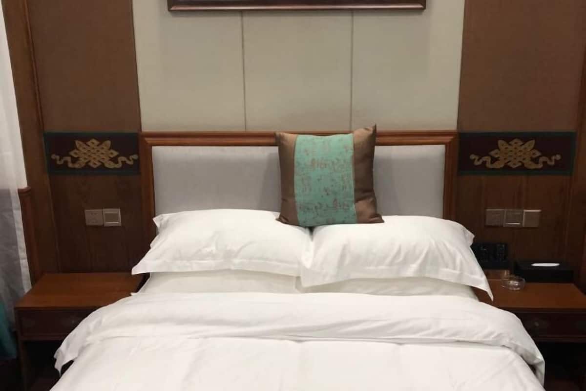 Ein Hotelzimmer mit einem Bett, einem Nachttisch und einer Wandleuchte.