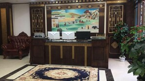 Un espace d’accueil agrémenté d’un grand tableau, d’un canapé en cuir, d’un bureau avec un ordinateur et d’une moquette à motifs.
