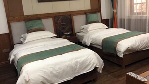 Deux lits avec des têtes de lit en bois, une literie blanche et une touche de couleur verte.