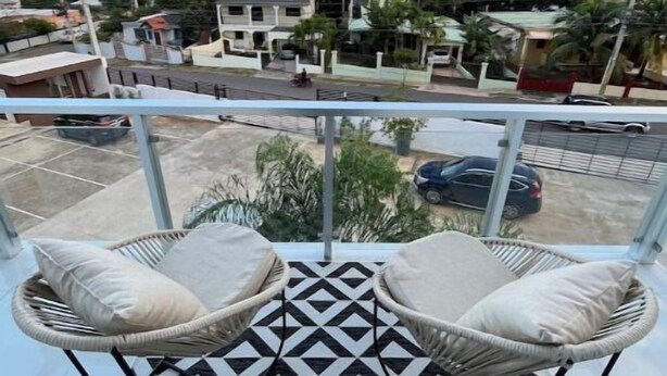 Un balcon avec deux fauteuils en osier et un tapis à motifs noirs et blancs.