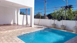 Une piscine rectangulaire à l’eau d’un bleu limpide, entourée d’une terrasse carrelée.