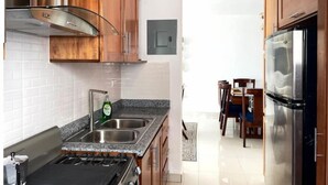 Une cuisine avec des meubles de rangement en bois, un évier en acier inoxydable, une cuisinière à gaz et un réfrigérateur.