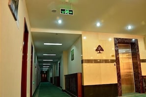 A hotel lobby with a long corridor, an elevator, and a reception desk.