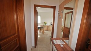 A hallway with wooden doors, a desk with papers, and a view into a dining area with a table and chairs. - Apartment Branka for 2 -3 person (Premantura)